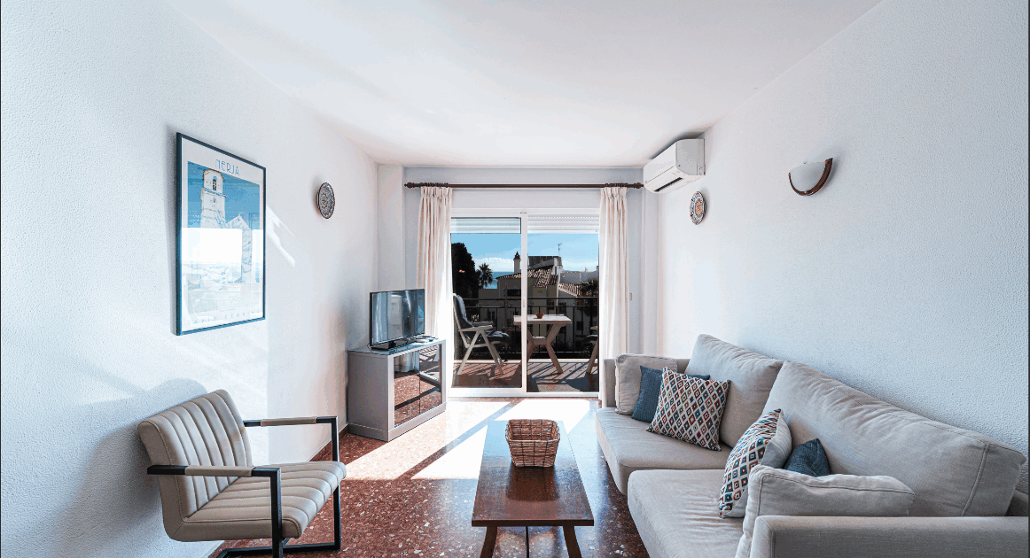 Vardagsrum i Acapulco 18 Casasol med utsikt över balkong, pool och hav – perfekt semesterboende i Nerja.